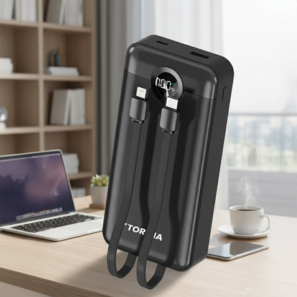 Siyah powerbank bağlı kablolarla %100 gösteriyor. Ahşap masada dizüstü bilgisayar, kahve fincanı ve telefon. Arkada raflar.