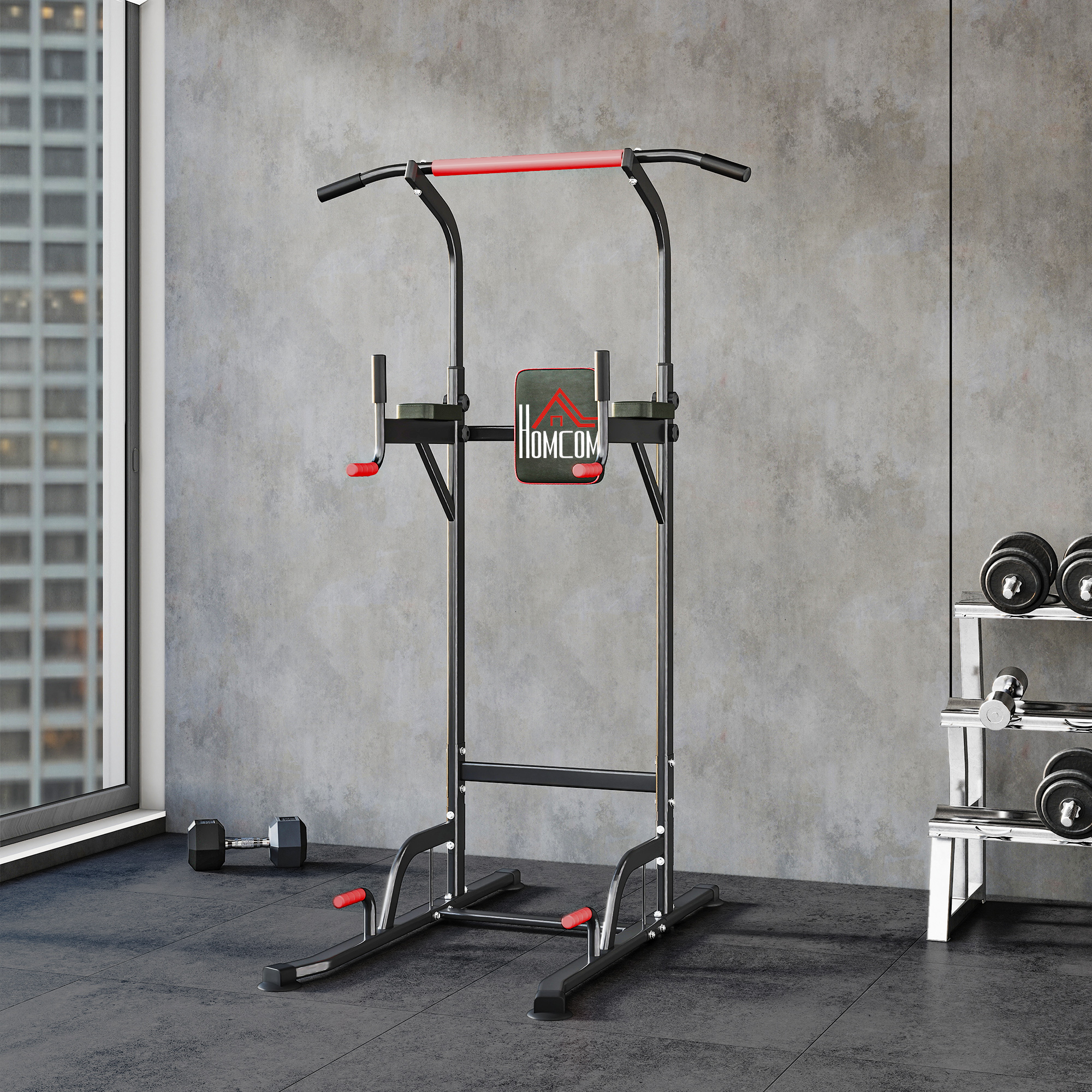 Una sbarra per trazioni nera e rossa si trova in una palestra. I manubri sono su un rack. Una finestra mostra una città.
