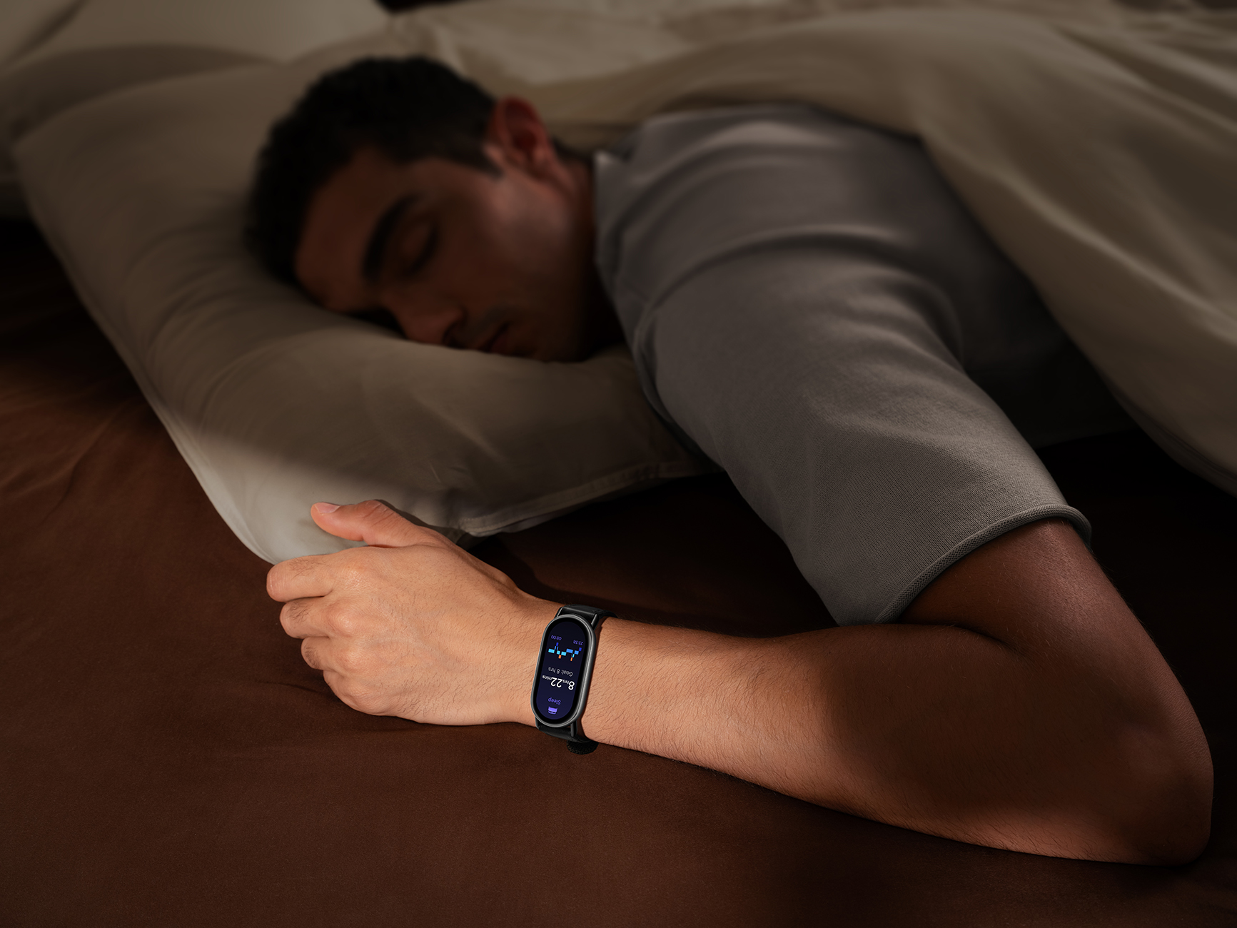 Un uomo dorme a letto, con un orologio. L'orologio mostra dati. È coperto da una coperta.