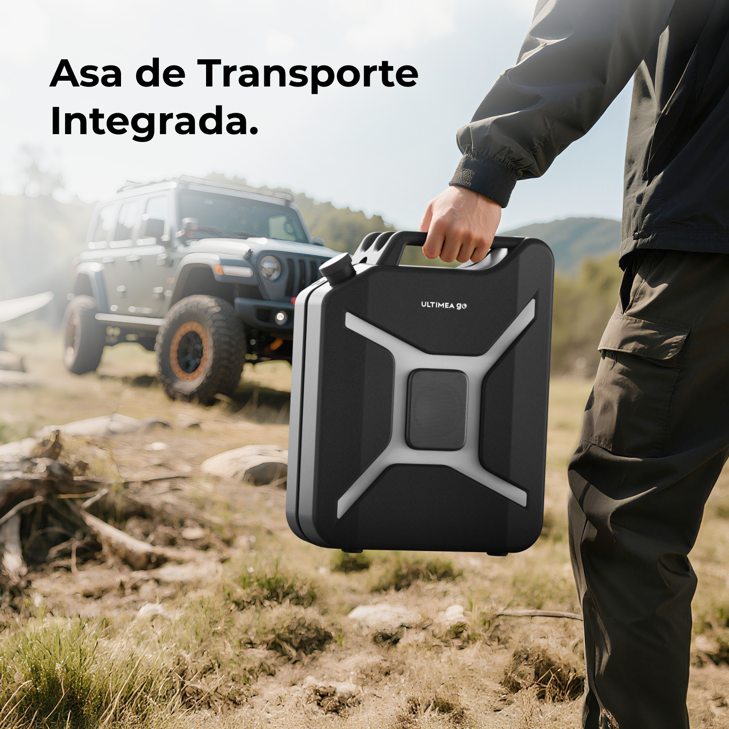 Una persona tiene in mano un altoparlante nero con una maniglia, in un ambiente naturale. Una Jeep sullo sfondo.