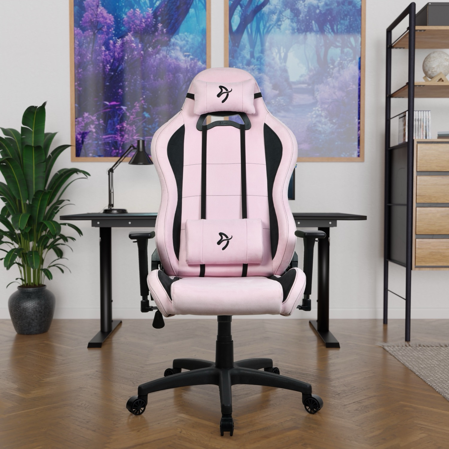 Een roze en zwarte gamestoel in een kamer. Een zwart bureau, een plant en kunst aan de muur op de achtergrond. Houten vloer.