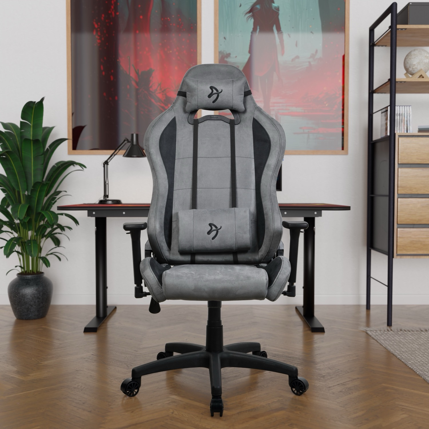 Ein grauer Gaming-Stuhl ist zentriert. Ein Schreibtisch, eine Pflanze und gerahmte Kunstwerke sind im Hintergrund. Holzfußboden.