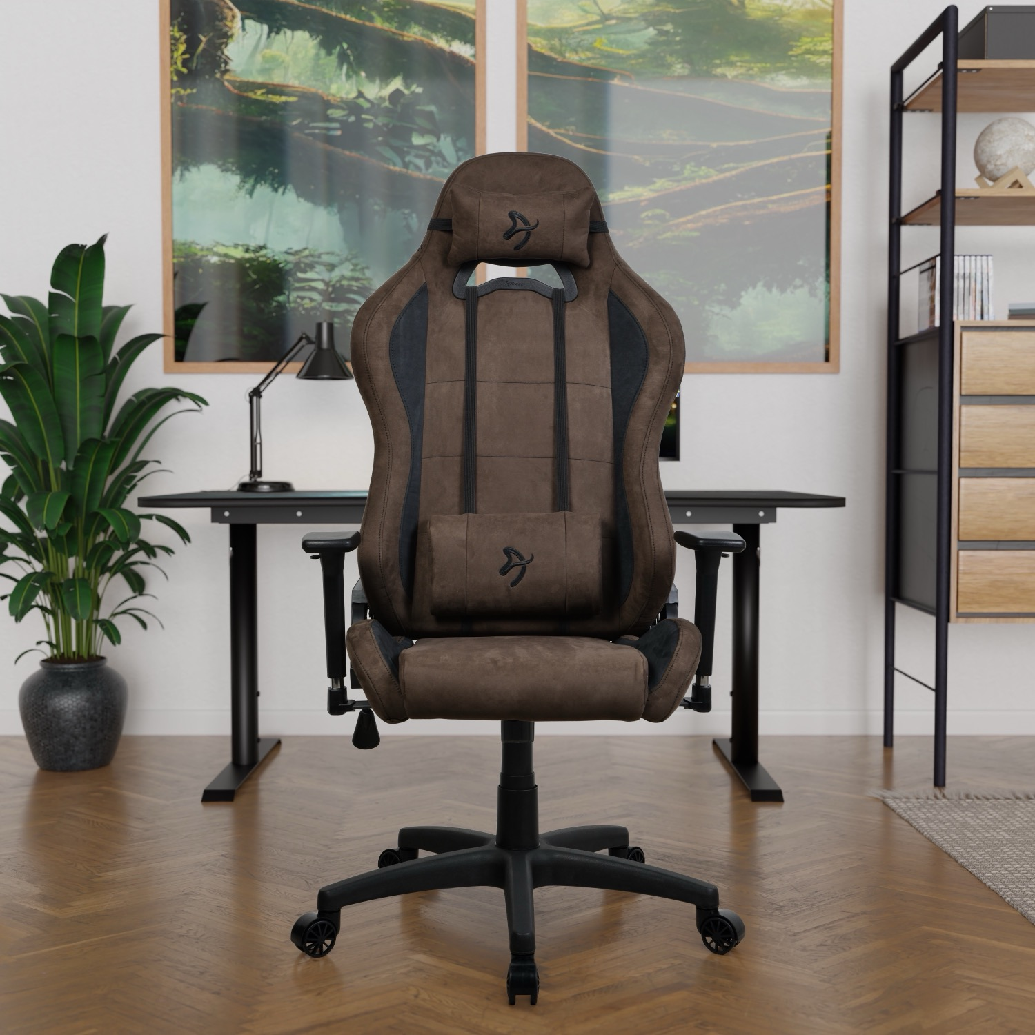 Een bruine gamestoel staat centraal. Achter de stoel staat een zwart bureau, een plant en twee ingelijste landschapsschilderijen. Rechts is een plank.