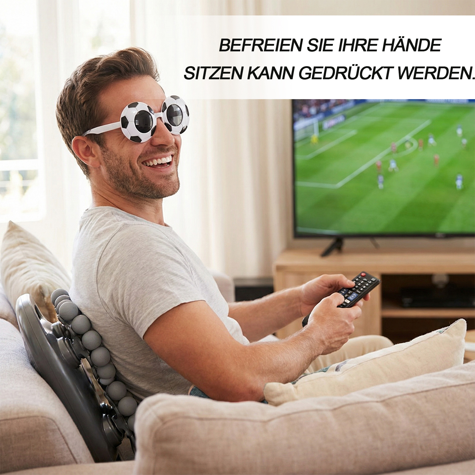 Mann mit Fußballbrille sieht fern, hält eine Fernbedienung. Ein Rückenmassagegerät ist hinter ihm. Text ist auf Deutsch.