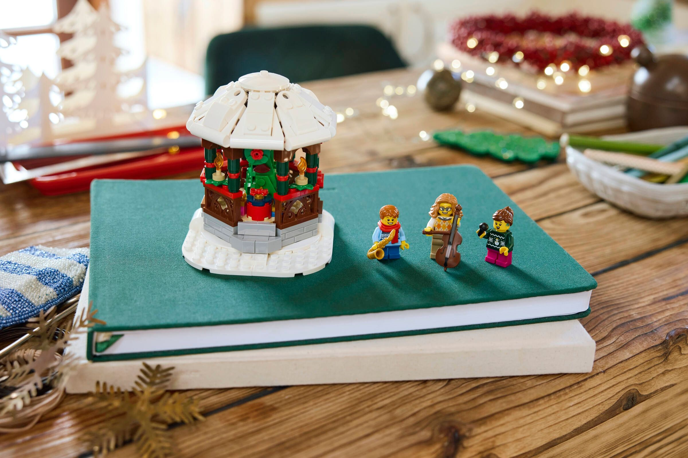 Ein Lego-Karussell und Figuren stehen auf einem Buch. Im Hintergrund sind Girlanden und Lichter.