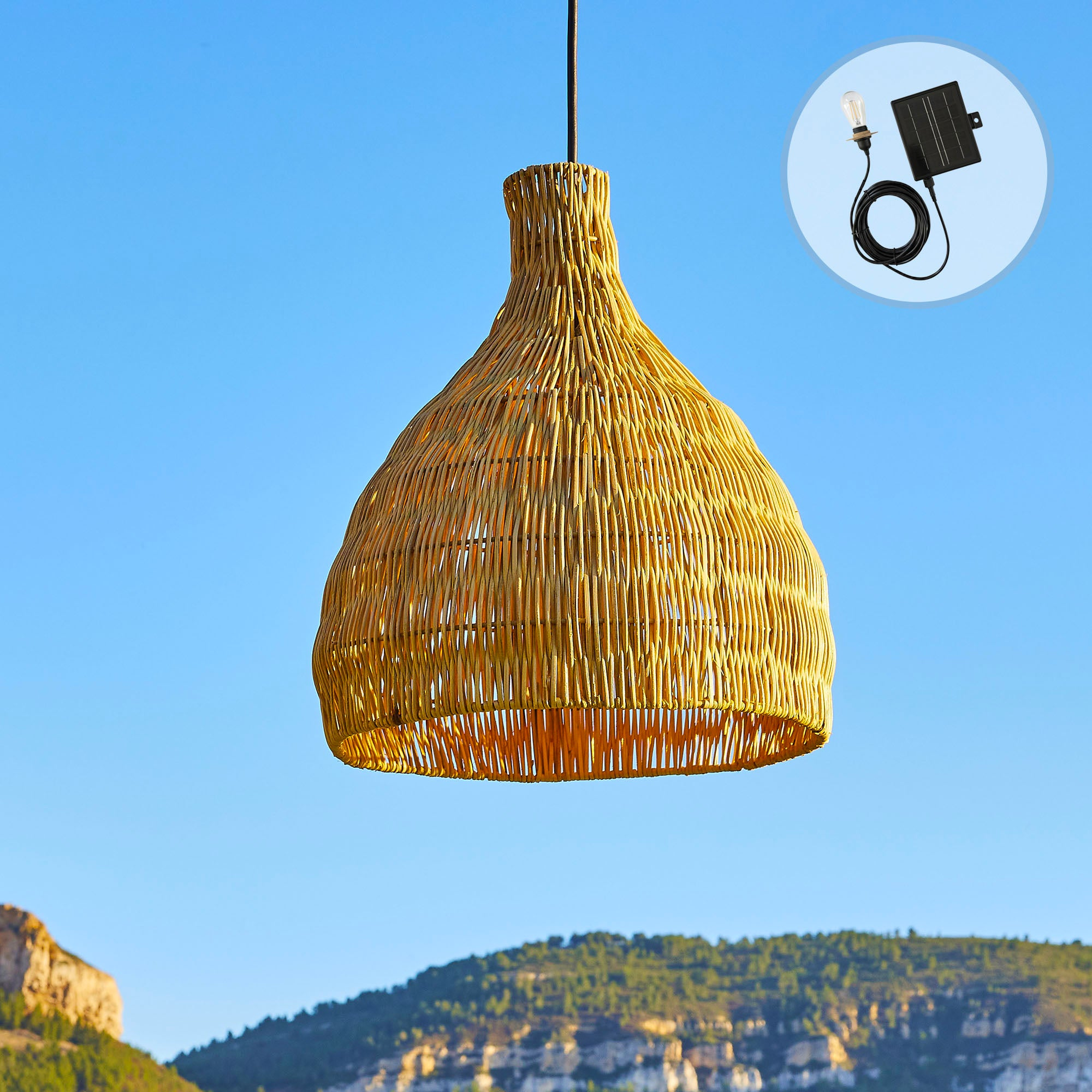Gewebte Lampe hängt vor blauem Himmel, Berge im Hintergrund und Solarpanel mit Glühbirne.