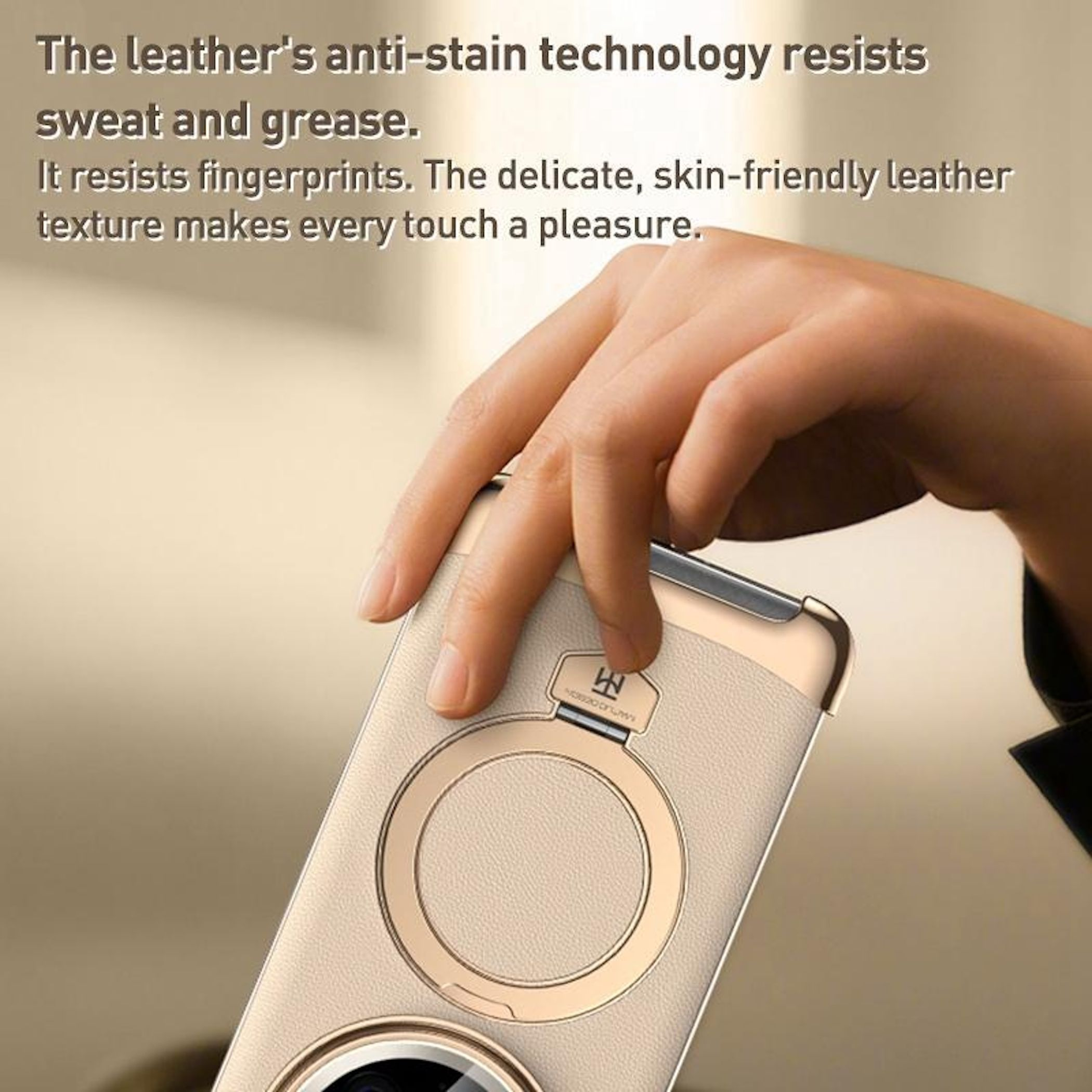 Eine Hand hält ein Telefon mit hellbeigem Leder auf der Rückseite. Das Telefon hat einen goldenen Ring und eine Kamera.