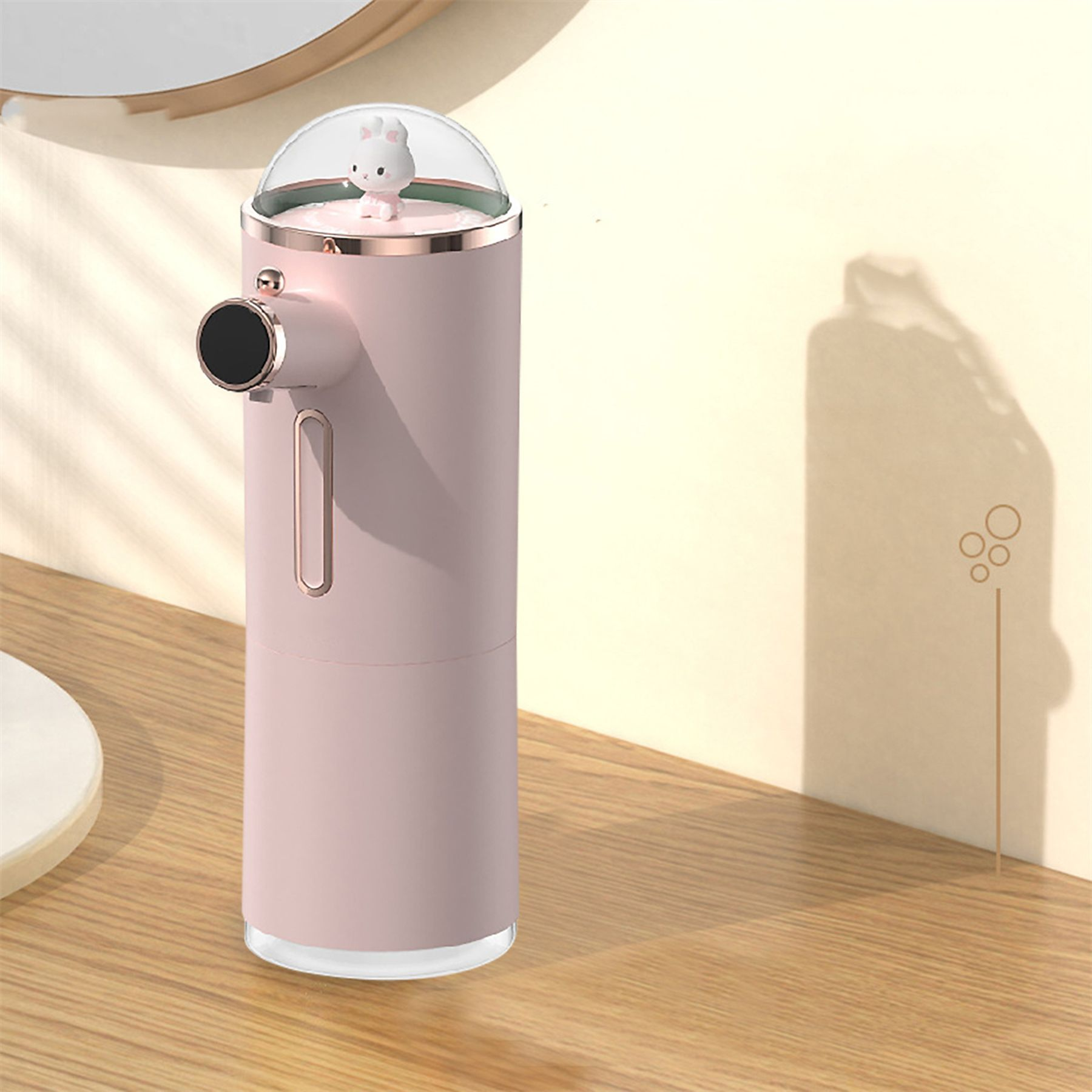 Ein rosa automatischer Seifenspender mit einer Hasenfigur oben, auf einer Holzoberfläche.
