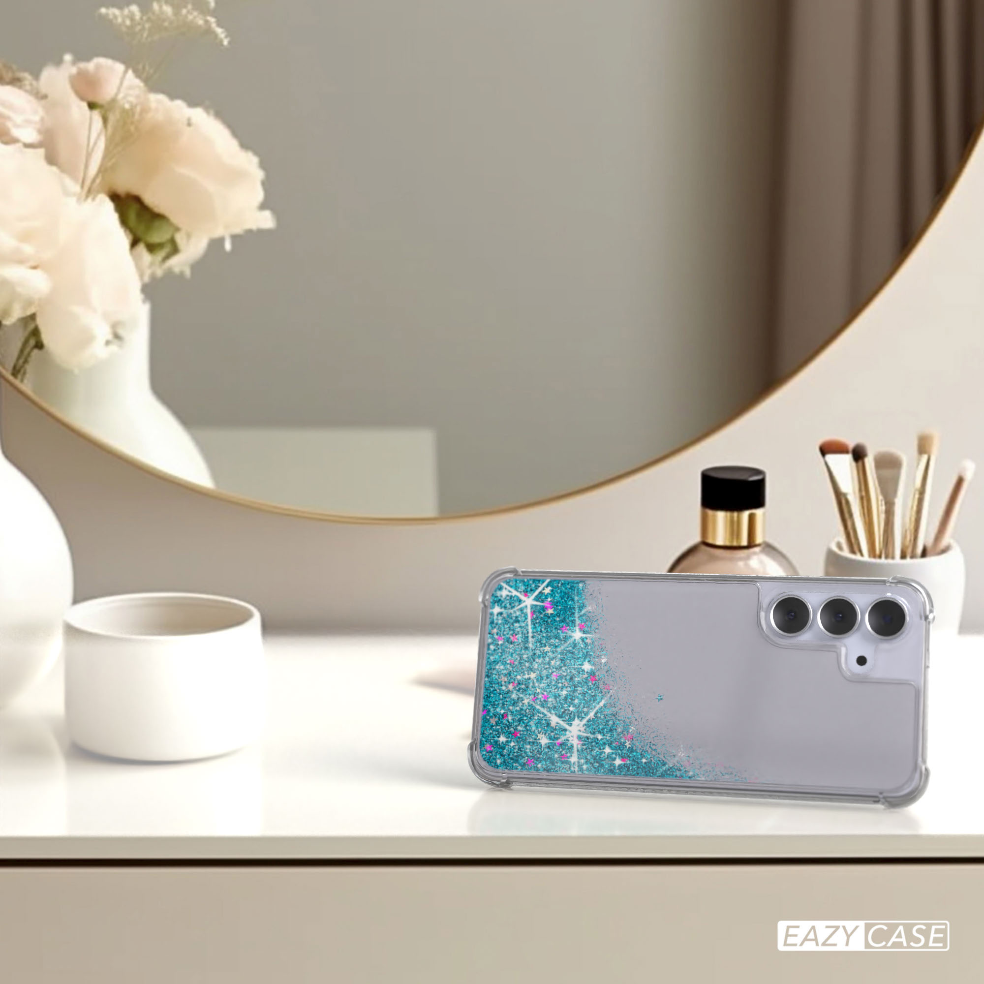 Eine Handyhülle mit Glitzer und ein Telefon auf einem Tisch mit Spiegel, Blumen und Kosmetika.