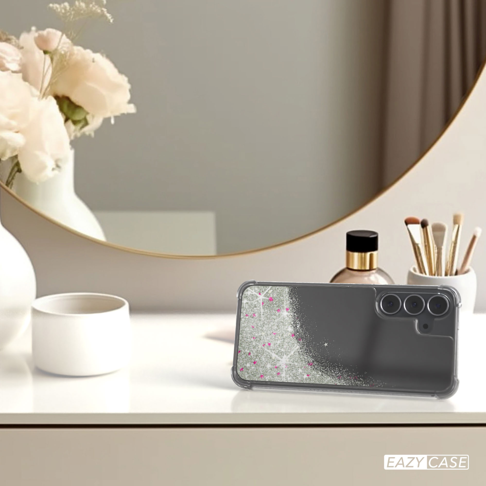 Auf einem Tisch liegt eine Handyhülle mit Glitzer und rosa Sternen. Blumen, Spiegel, Parfüm und Make-up-Pinsel sind im Hintergrund.