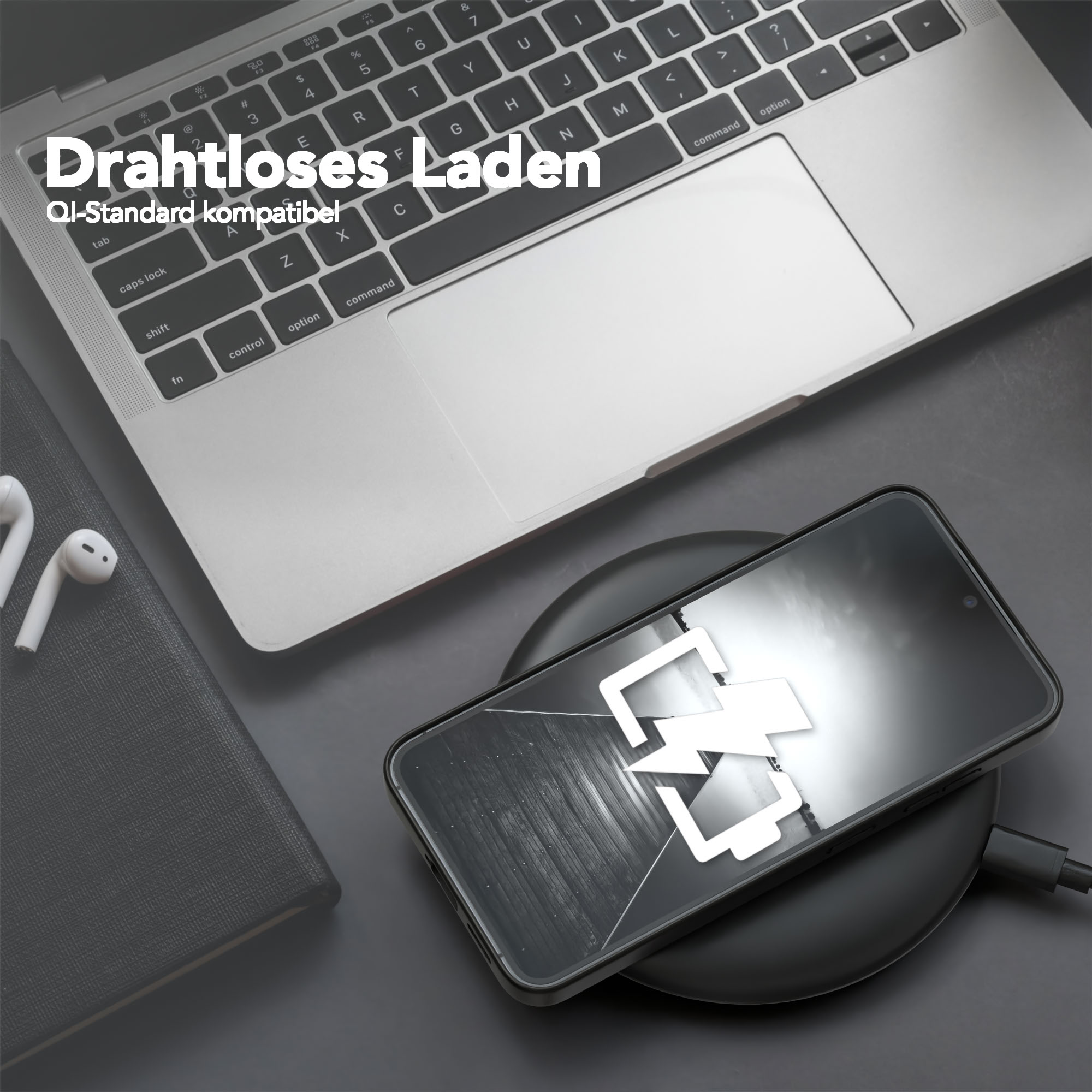 Ein Telefon, das drahtlos auf einem schwarzen Pad geladen wird. Ein Laptop und Ohrhörer sind ebenfalls im Bild. Das Telefon zeigt ein Ladesymbol.