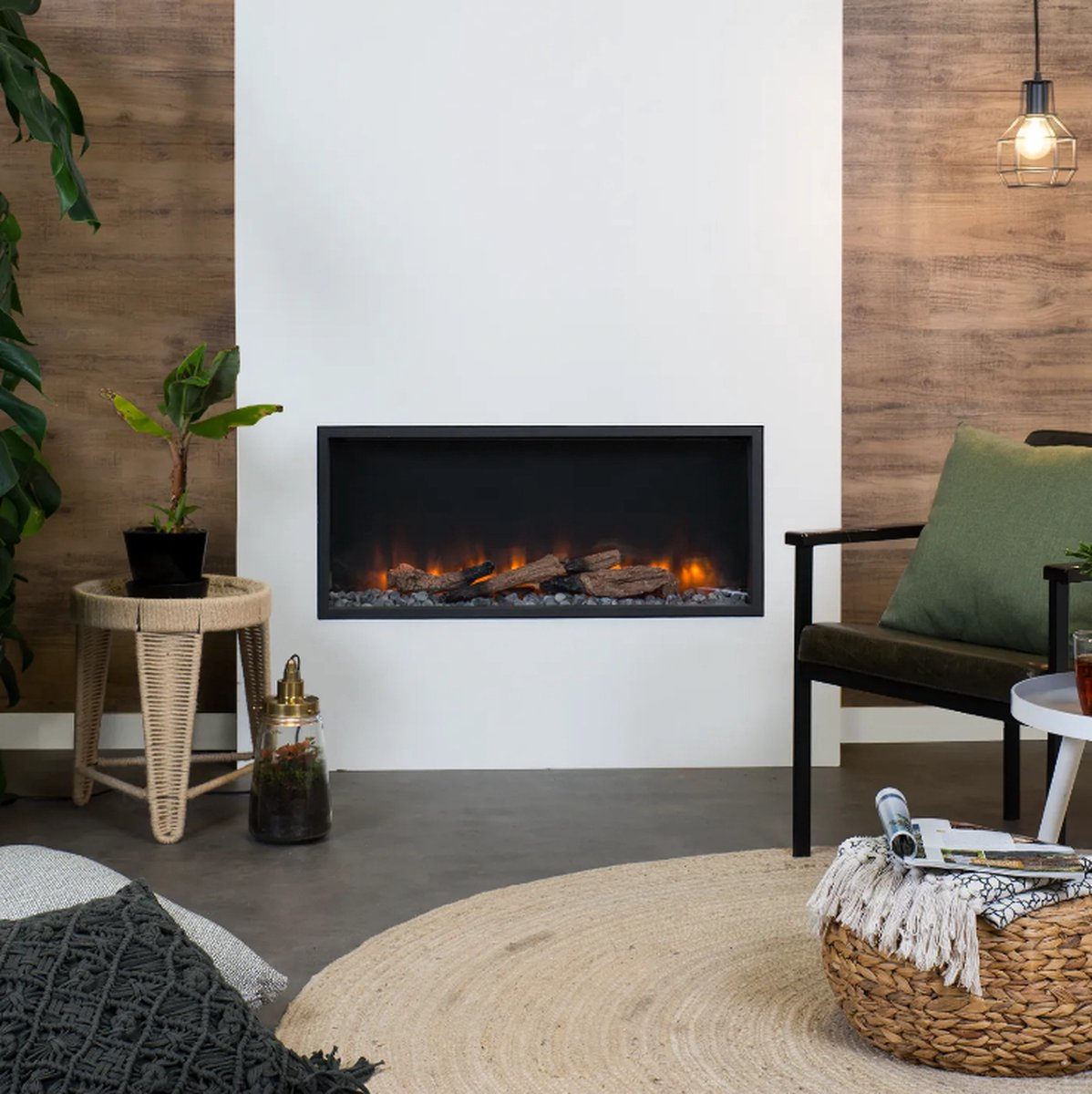 Woonkamer met elektrische open haard, stoel, planten, vloerkleed en een kleine tafel. De open haard heeft een zwart frame.