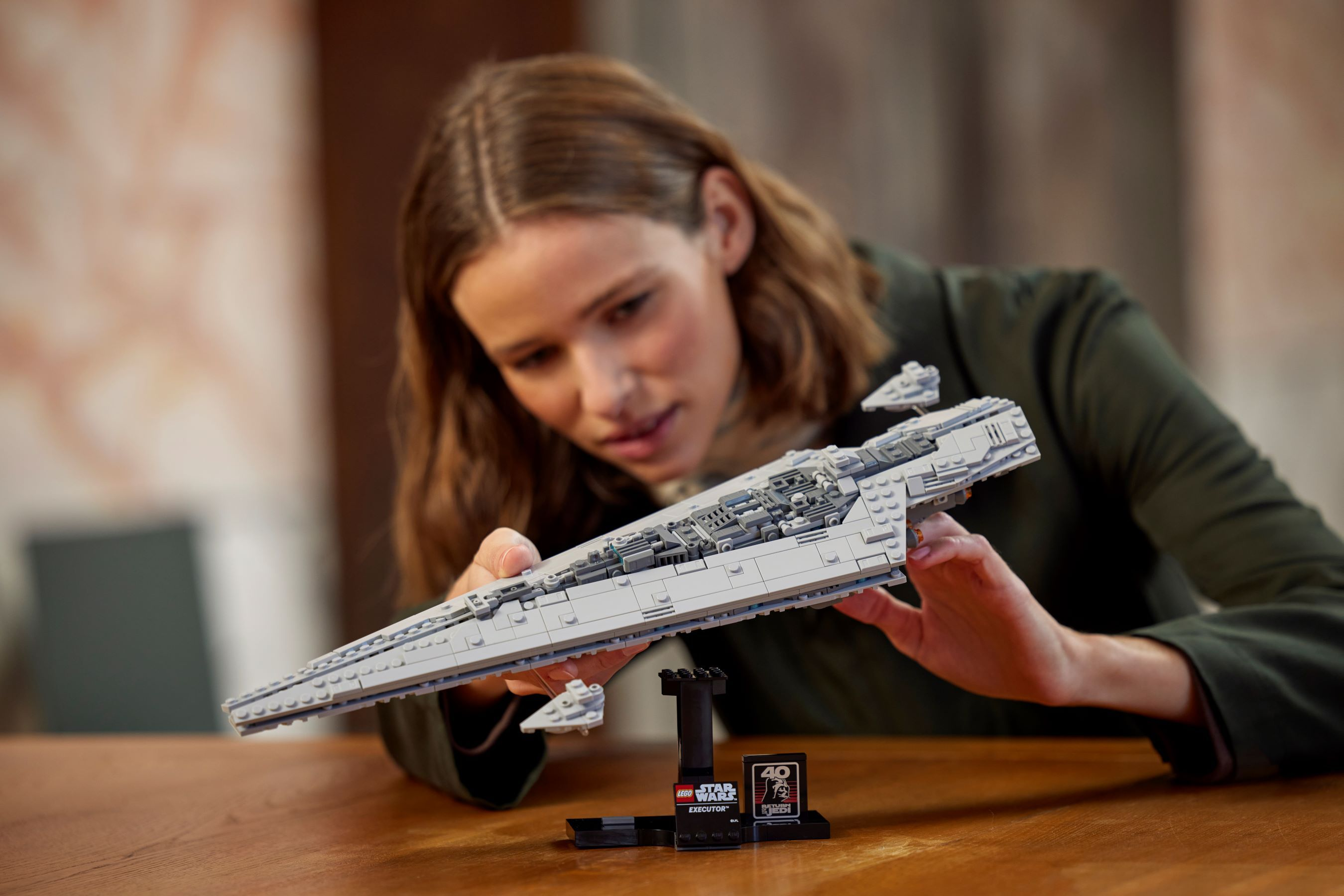 Una donna esamina un modello Lego di Star Wars di una nave. Il modello è grigio e sotto c'è un supporto nero.