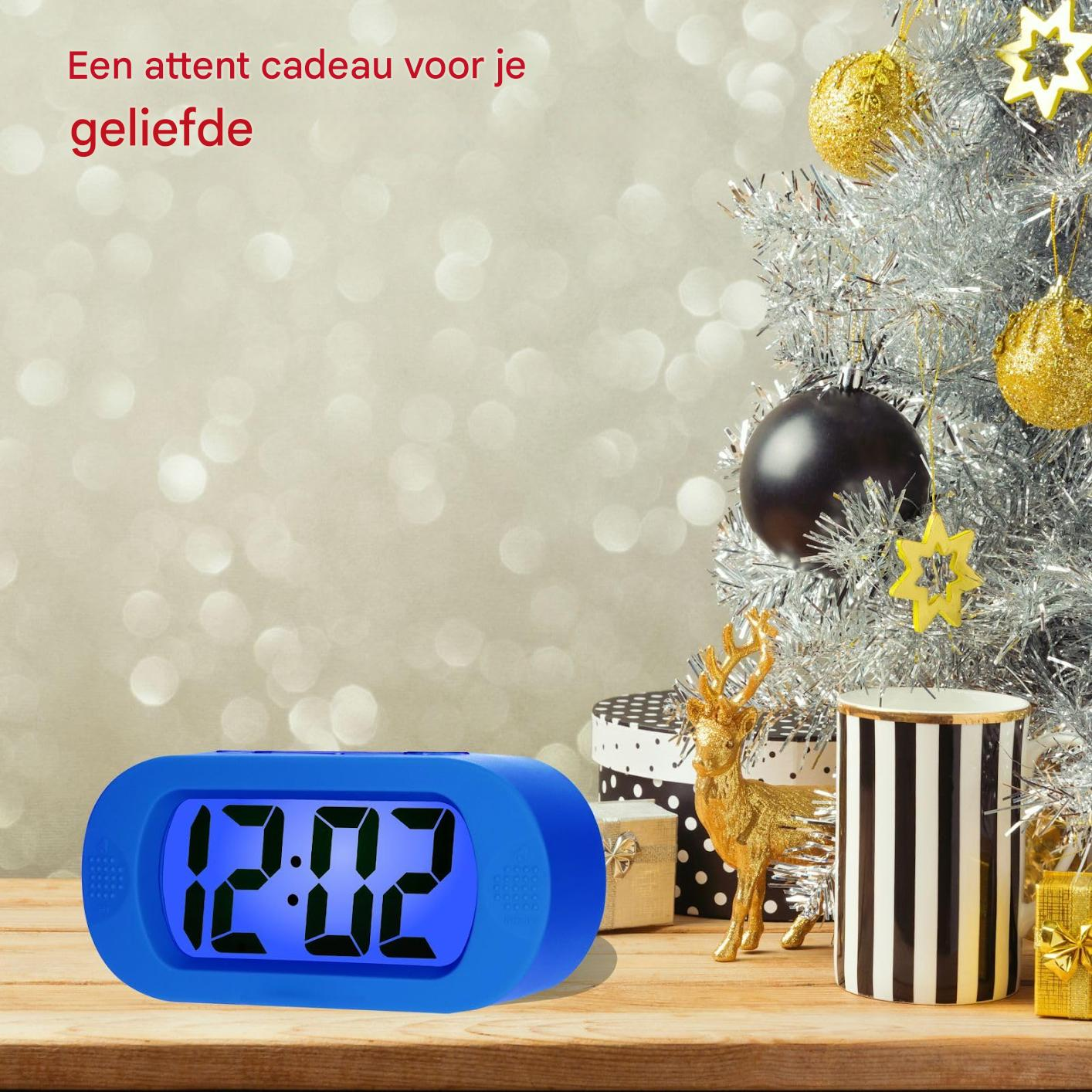 L'orologio digitale blu mostra le 12:02. Le decorazioni natalizie includono albero, ornamenti, regali e una statuina di cervo dorato.