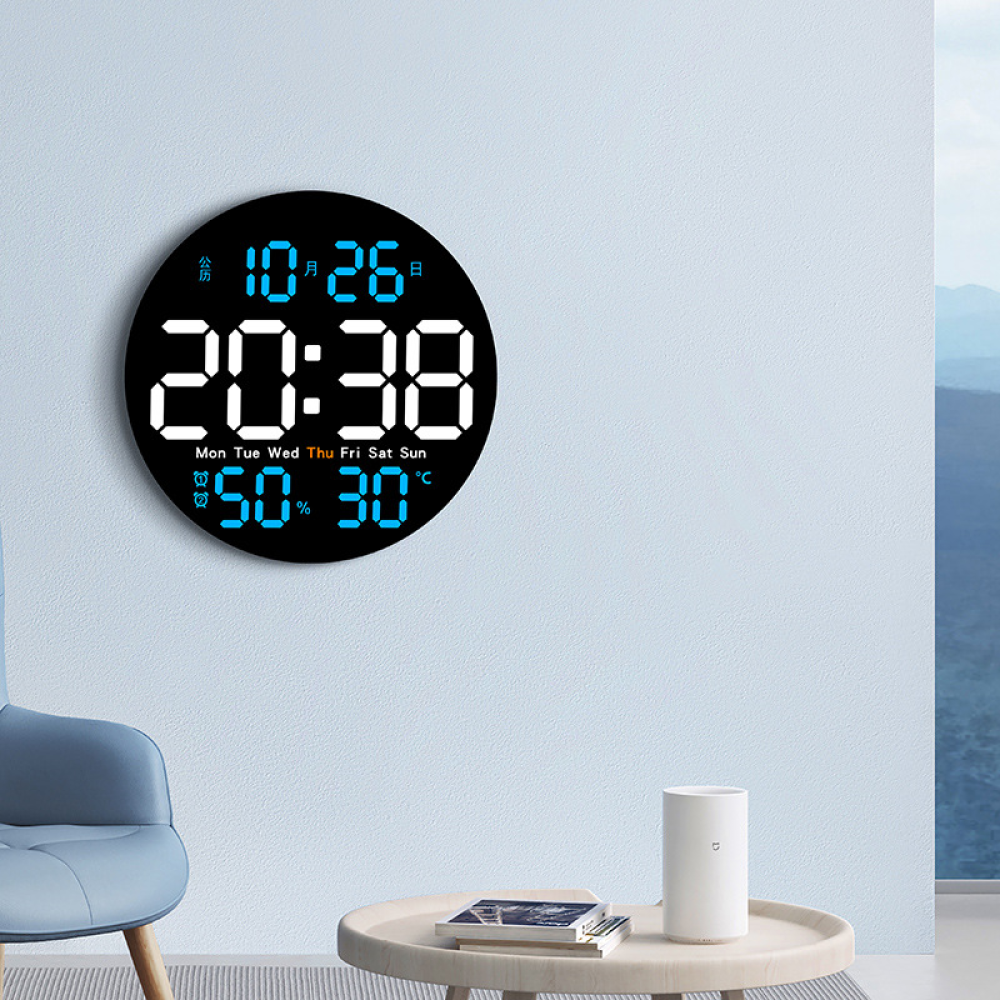 Un orologio digitale mostra l'ora, la data e l'umidità. È su un muro blu. Una sedia e un tavolino sono nella scena.