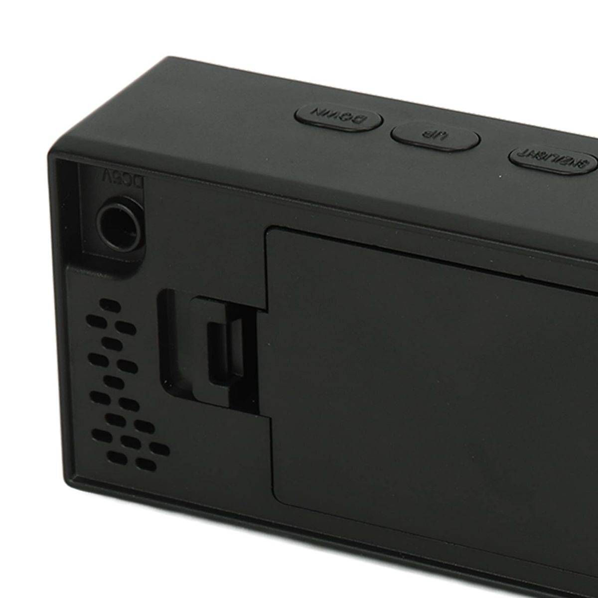 Nahaufnahme eines schwarzen elektronischen Geräts mit den Tasten 'Down', 'Up' und 'Snooze/Light'. Es hat einen DC-Eingang und ein Fach.