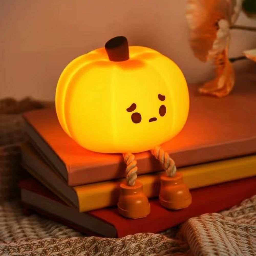 Una lampada a forma di zucca luminosa con una faccia triste è seduta sui libri. Ha gambe di corda e piedi arancioni. Lo sfondo mostra fiori.