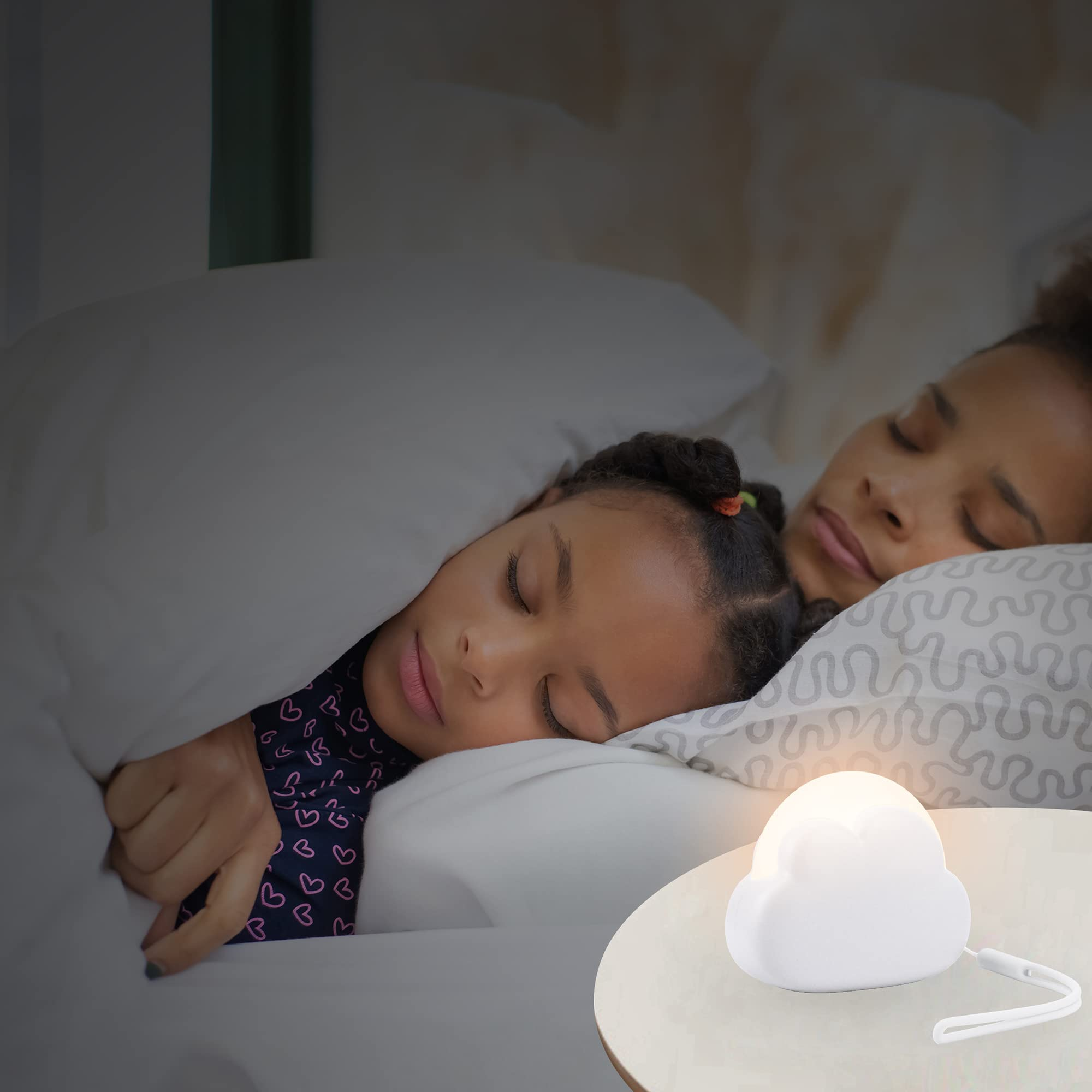 Una madre e un bambino dormono a letto. Una lampada a forma di nuvola è su un tavolo. La scena è scarsamente illuminata.
