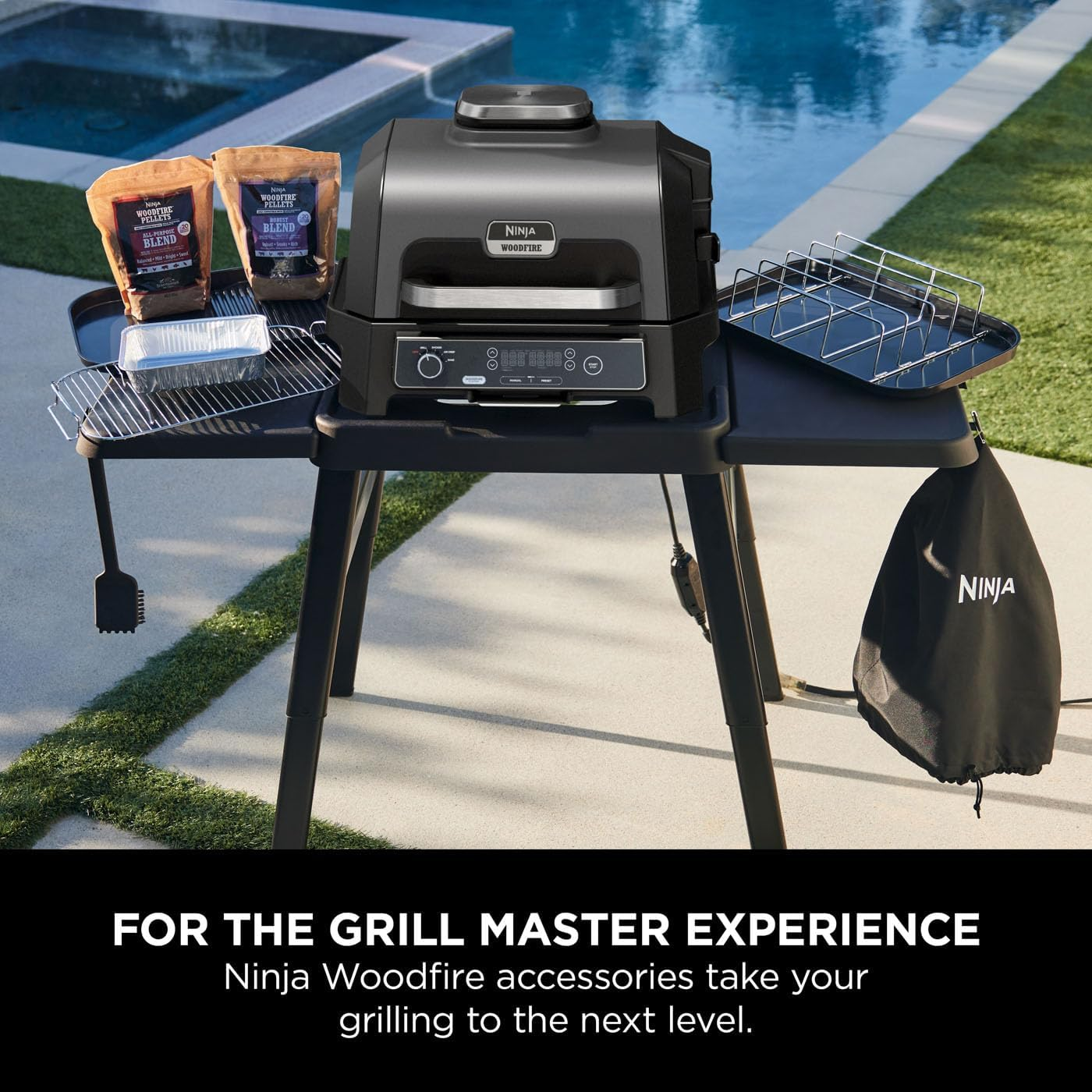 Griglia Ninja Woodfire con accessori. Include pellet, griglie e una copertura. Su un tavolo nero, vicino a una piscina.