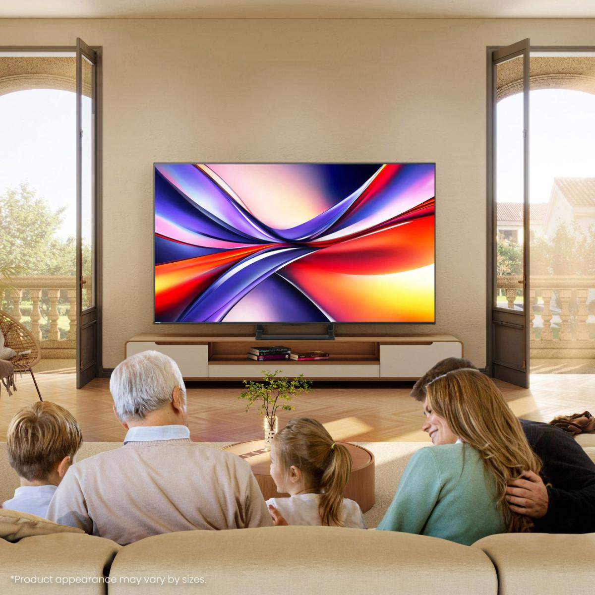 Famille regardant la télévision. Un grand écran affiche un art abstrait coloré. Fenêtres des deux côtés. Les gens sont assis sur un canapé.