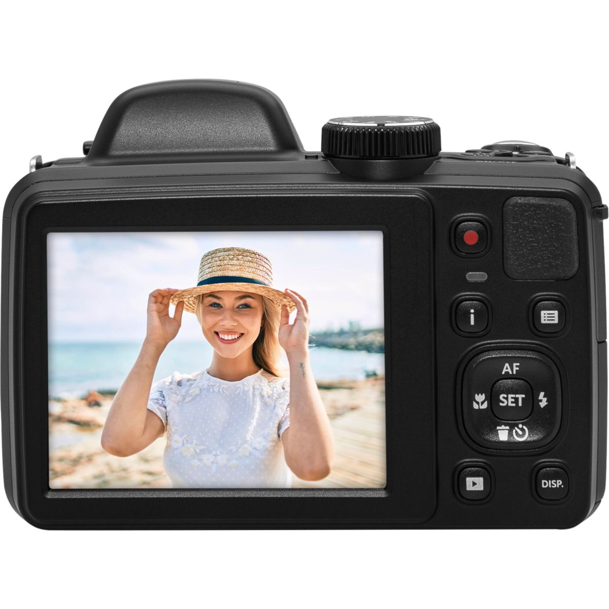 Czarny aparat pokazuje uśmiechniętą kobietę w kapeluszu nad morzem. Przyciski i pokrętło są widoczne na aparacie.