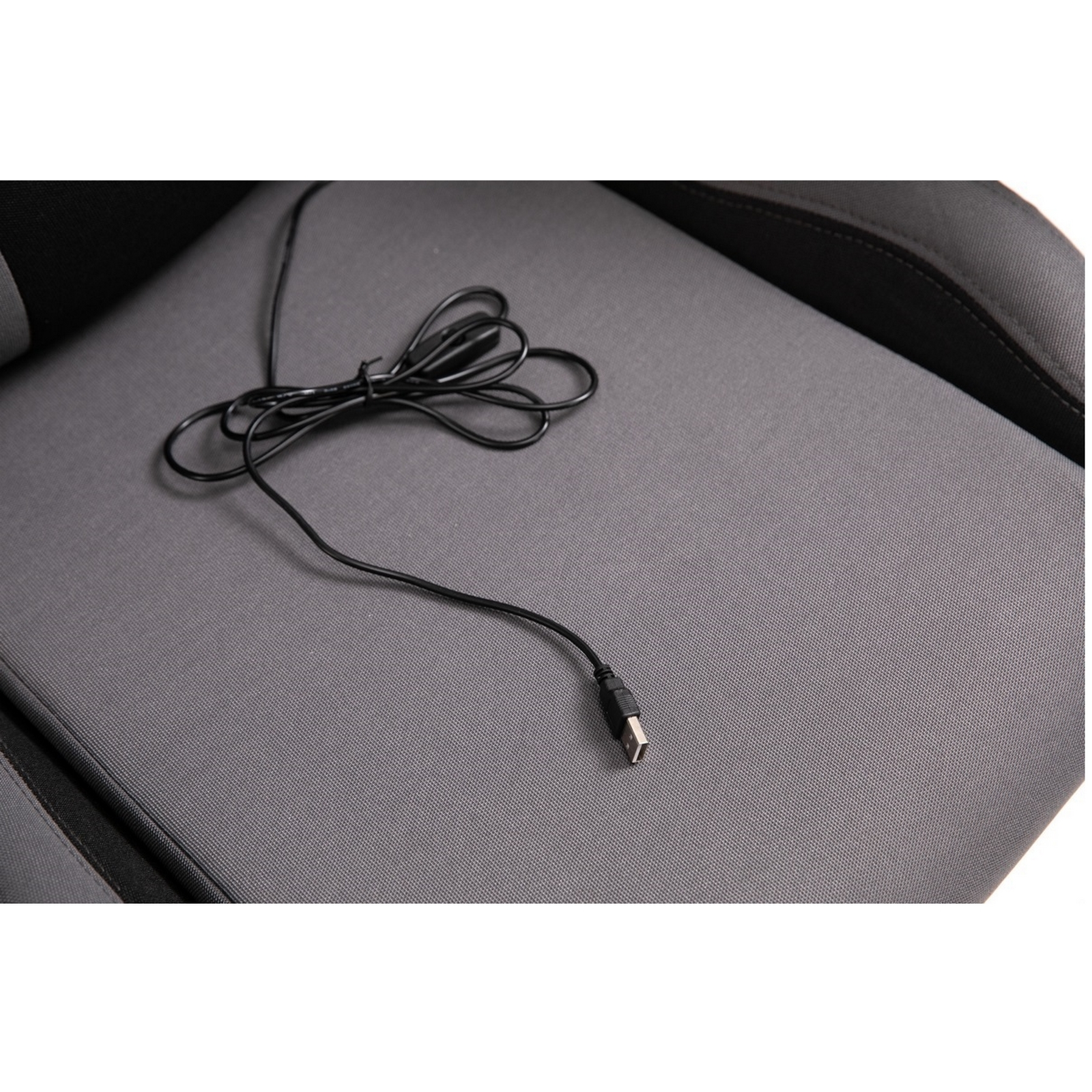 Nahaufnahme eines Gaming-Stuhlsitzes mit einem schwarzen USB-Kabel. Der Sitz ist grau, das Kabel liegt darauf.