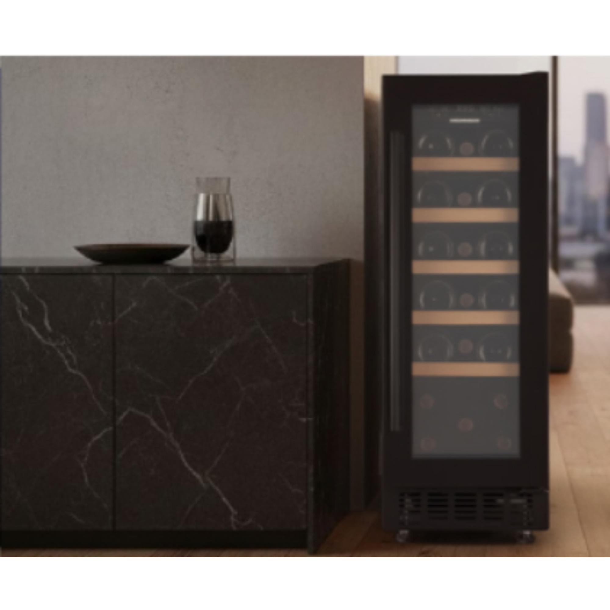 A wine cooler stands beside a dark marble cabinet. A wine glass sits on top. City view in background.