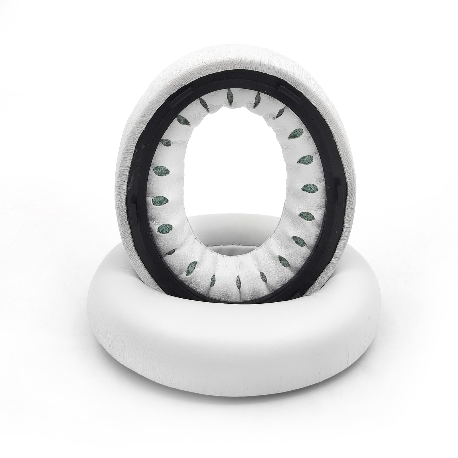 Dwie białe poduszki nauszne do słuchawek. Górna znajduje się wewnątrz drugiej. Widoczne są czarne i zielone akcenty.