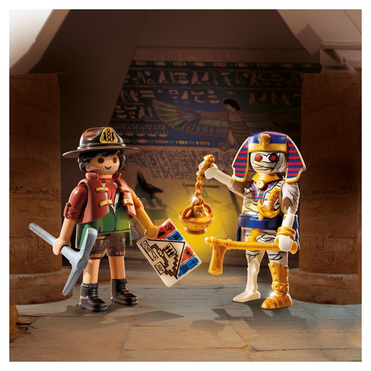 Dwie figurki Playmobil: odkrywca z kilofem i mapą, naprzeciwko mumii ze złotą lampą i berłem.