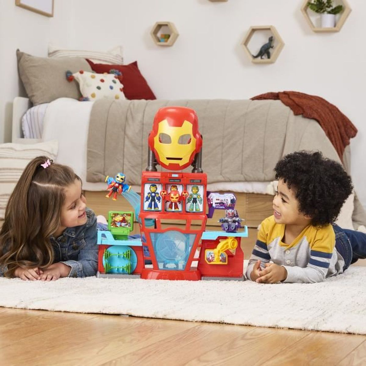 Dos niños miran un juguete de Iron Man. El juguete es rojo con una máscara de Iron Man encima y pequeñas figuras.