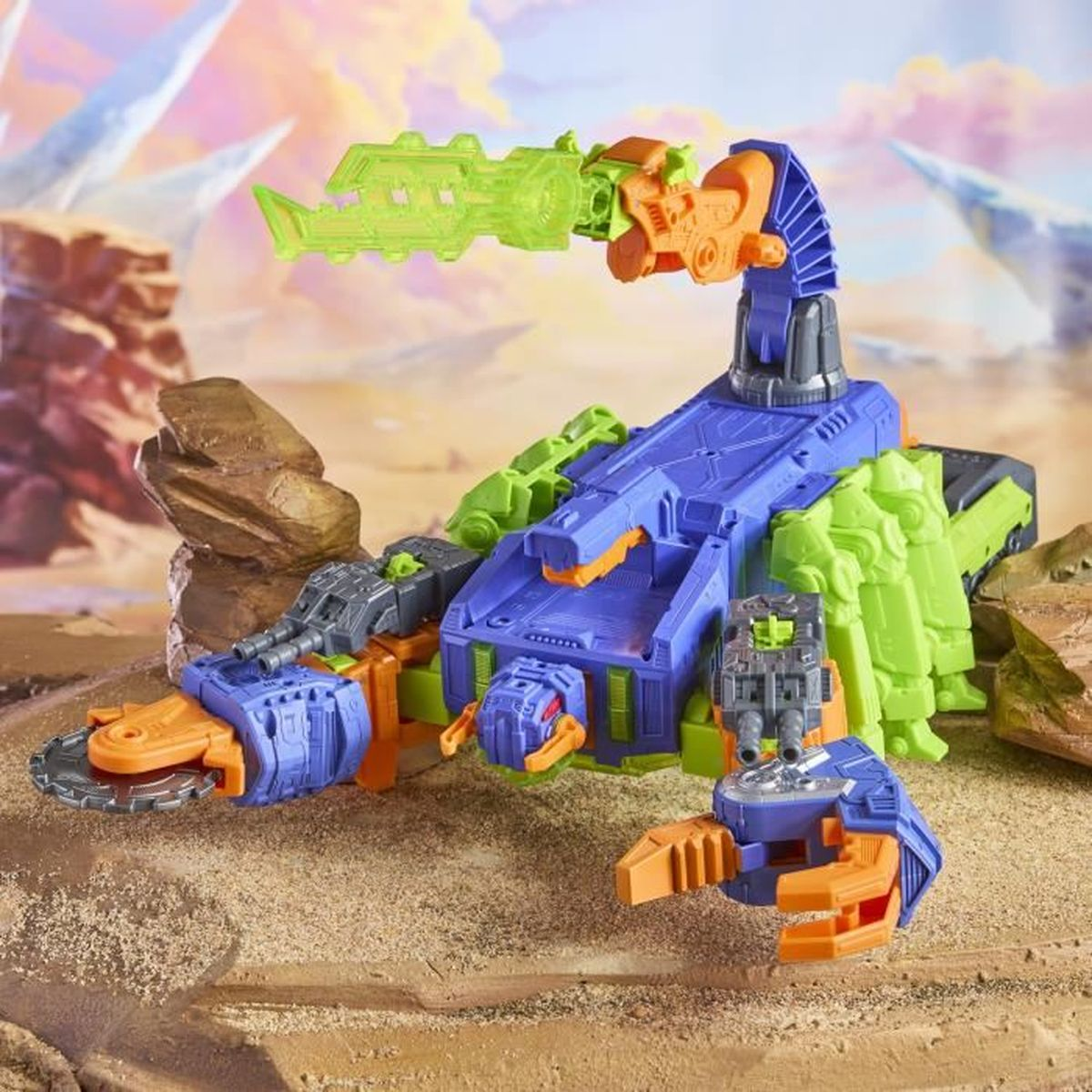 Ein buntes Spielzeug-Skorpion mit blauen, grünen und orangen Teilen. Es steht auf einer sandigen Oberfläche mit einem Fantasy-Hintergrund.