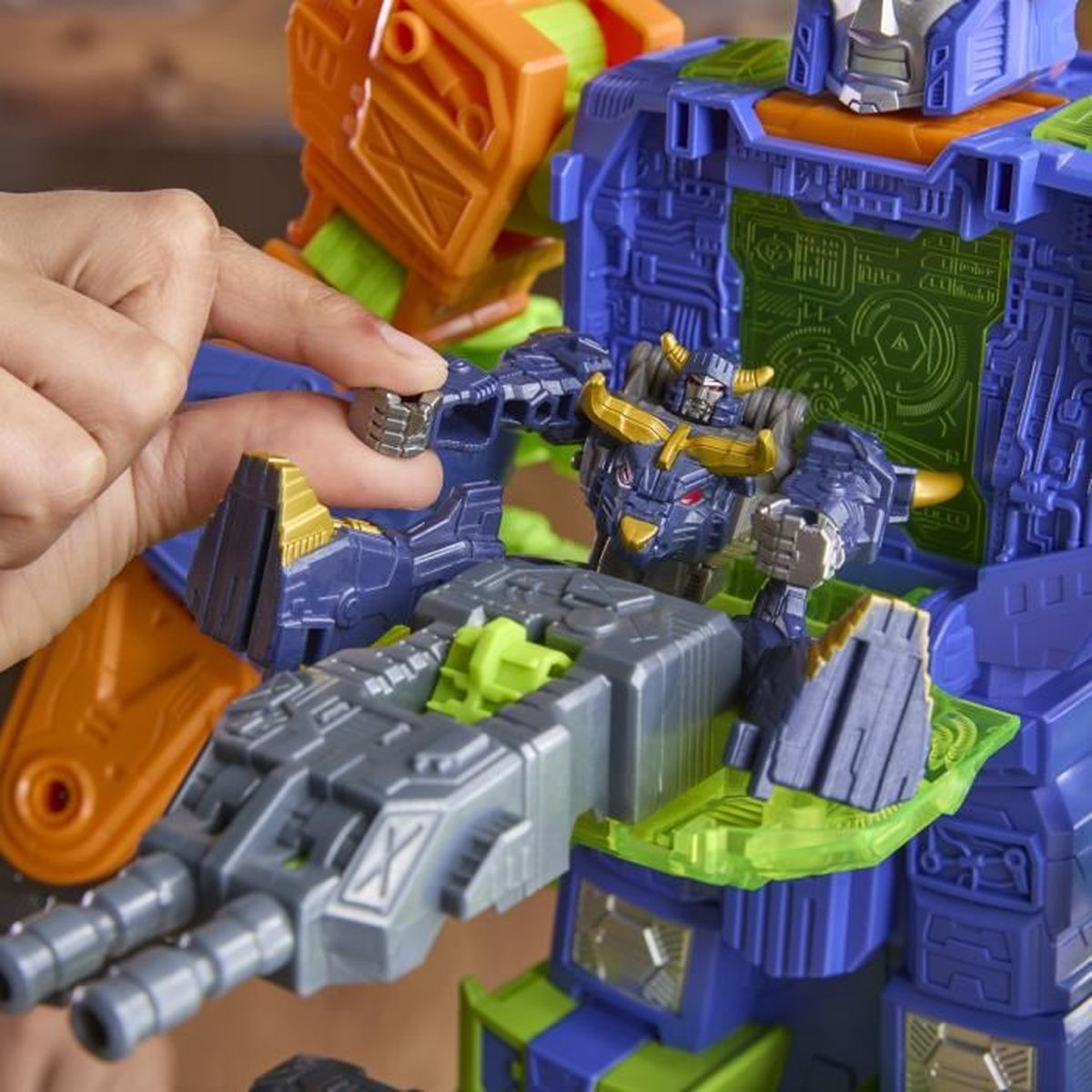 Eine Hand platziert eine kleine Roboterfigur in ein größeres, mehrfarbiges Roboterspielzeug. Das Spielzeug ist blau, orange und grau.