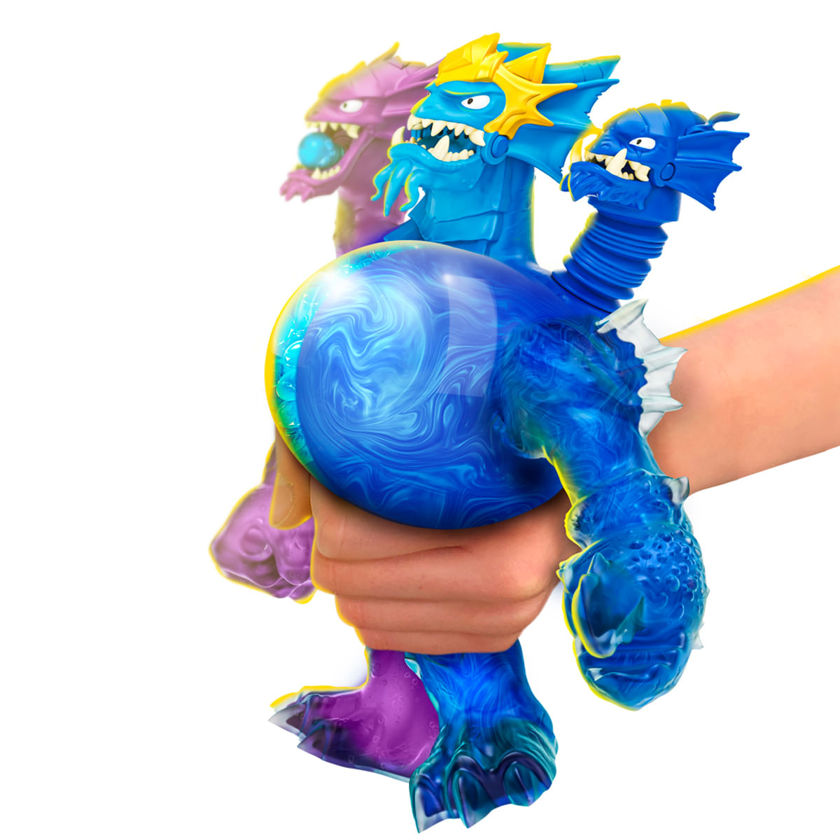 Una mano sostiene un dragón de juguete azul con una bola transparente, hay dos dragones más en el fondo, uno morado y otro azul.