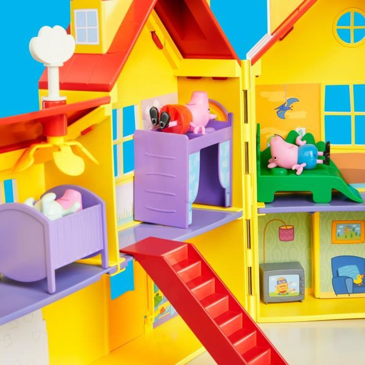 Una casa de juguete amarilla y roja con figuras de Peppa Pig. Incluye camas, escaleras, una TV y un ventilador.