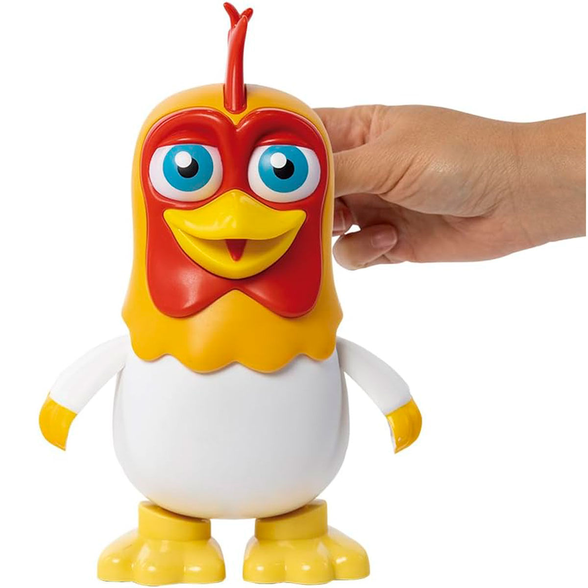 Un juguete de pollo amarillo y rojo con ojos azules, sostenido por una mano. Tiene cuerpo blanco y patas amarillas.