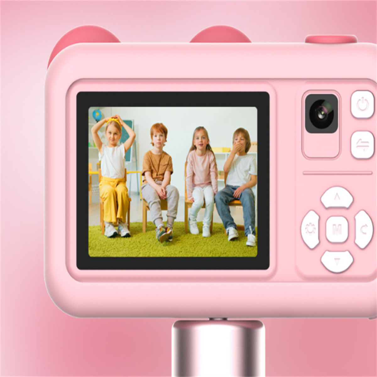 Een roze camera toont vier kinderen op stoelen. Eén kind heeft de handen omhoog, een ander bedekt de mond. Achtergrond is een klaslokaal.