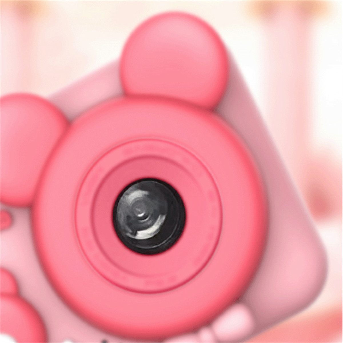 Een close-up van een roze speelgoedcamera. De lens is zwart en gecentreerd, omringd door een roze cirkel. De camera heeft afgeronde kenmerken.