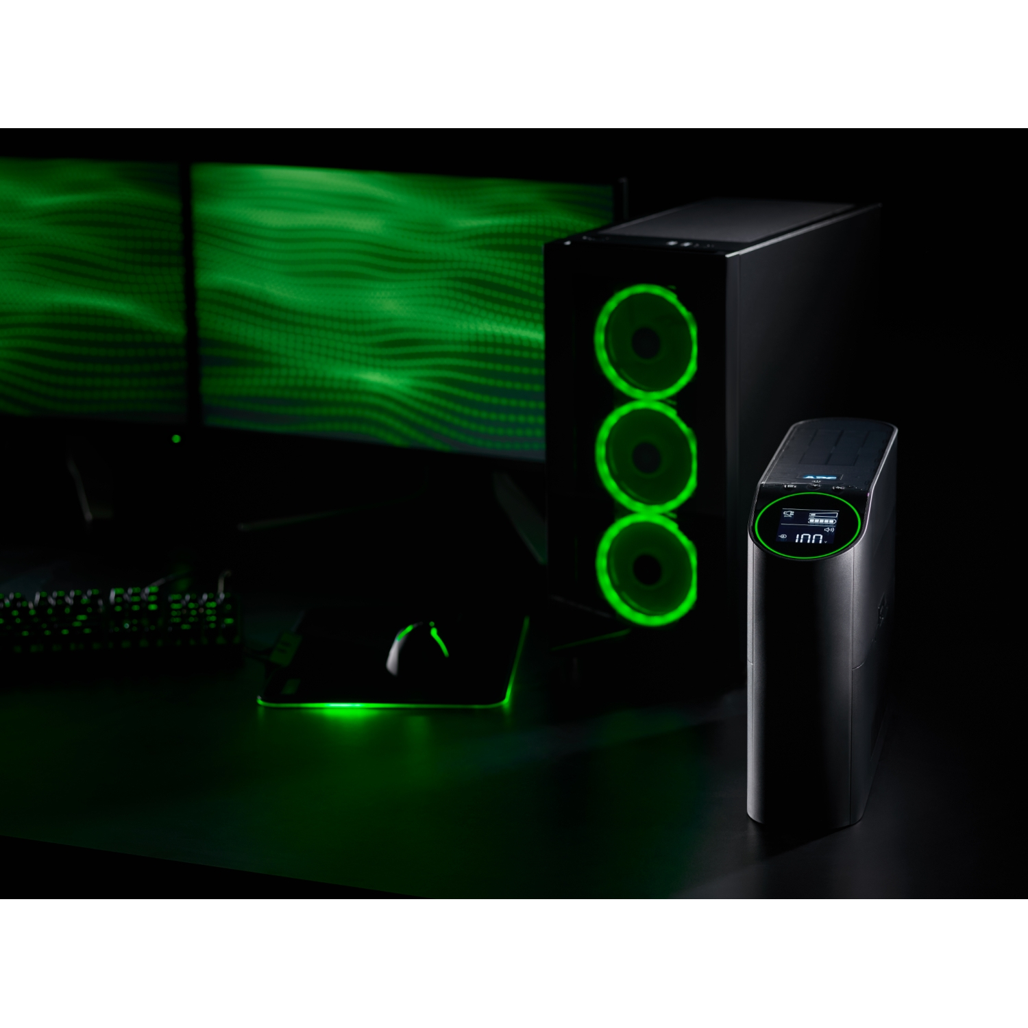 Un'impostazione PC gaming con illuminazione verde. Include un case del computer, un monitor, un mouse e un UPS. L'impostazione è su una superficie nera.