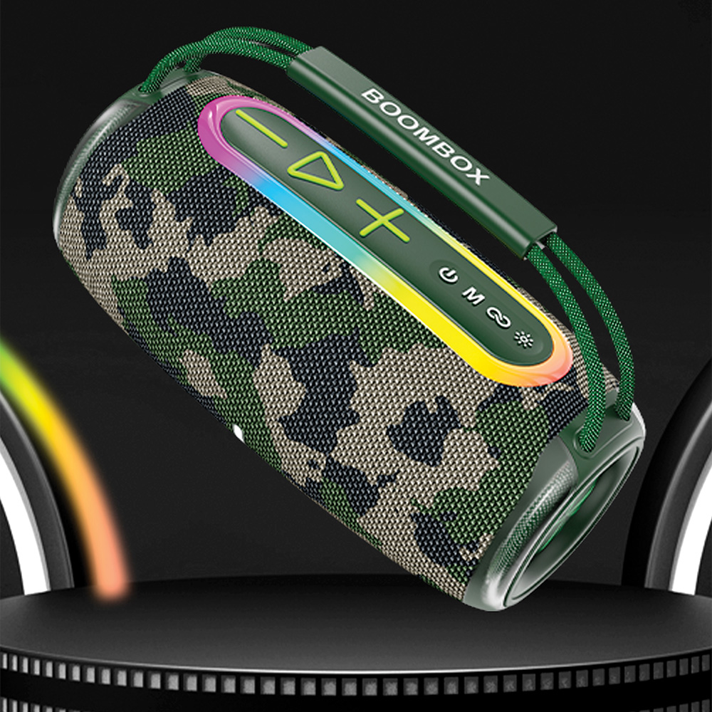 Yeşil detaylara ve kontrollere sahip kamuflaj desenli bir boombox hoparlör. Bir tutacağı var ve koyu bir platformda duruyor.
