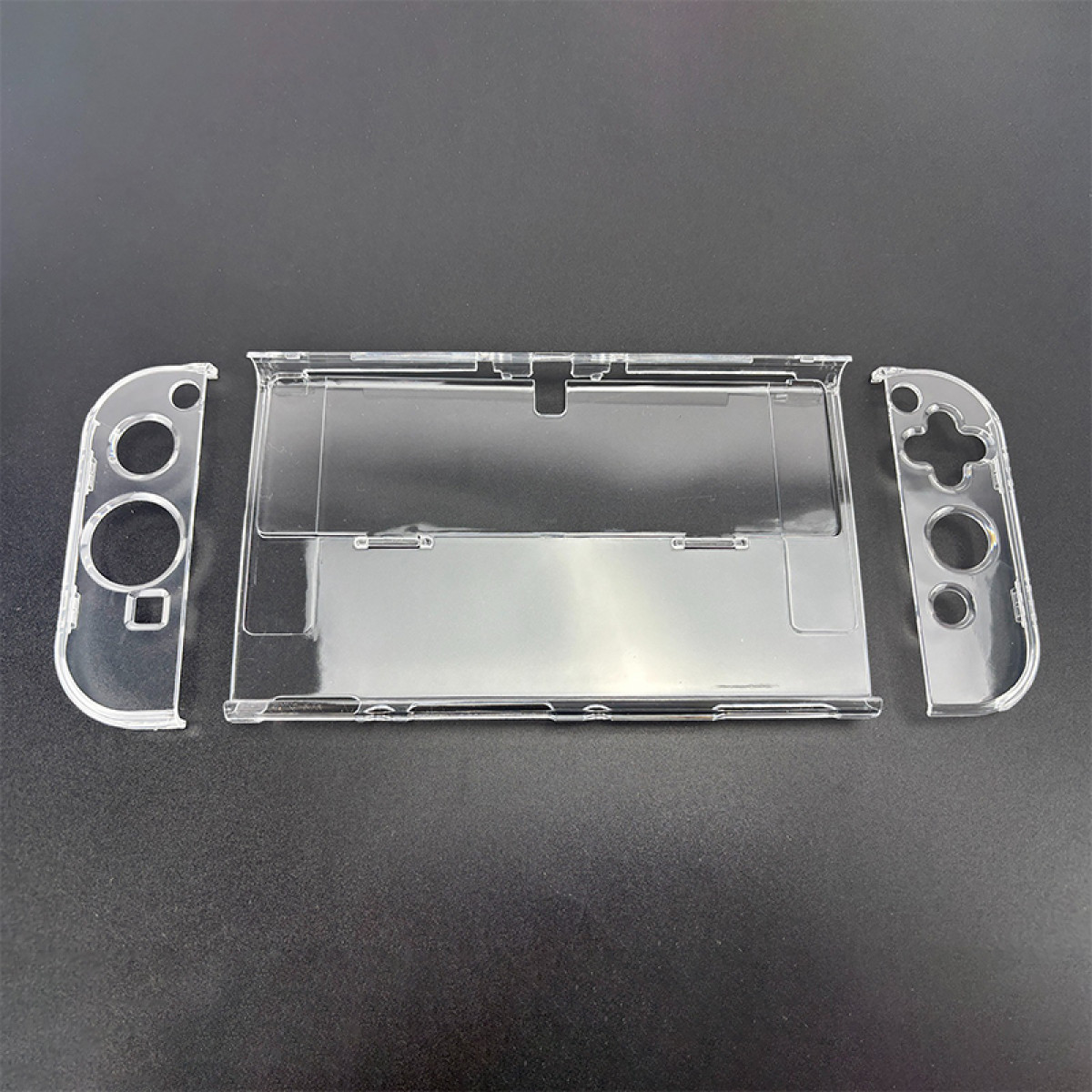 Pièces de boîtier Nintendo Switch en plastique transparent posées sur une surface noire. Comprend le corps principal et deux pièces de manette.