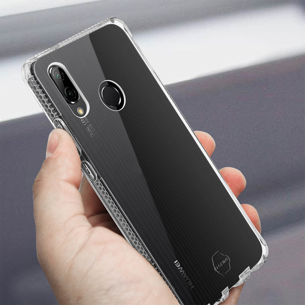Una mano tiene una custodia trasparente per telefono. La custodia ha un retro nero e un bordo trasparente. Il logo Huawei è visibile.