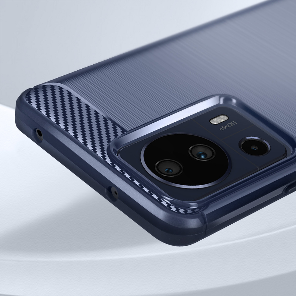 Primo piano di una custodia blu per telefono con modulo fotocamera. La custodia ha un accento in fibra di carbonio. Lo sfondo è sfocato e bianco.