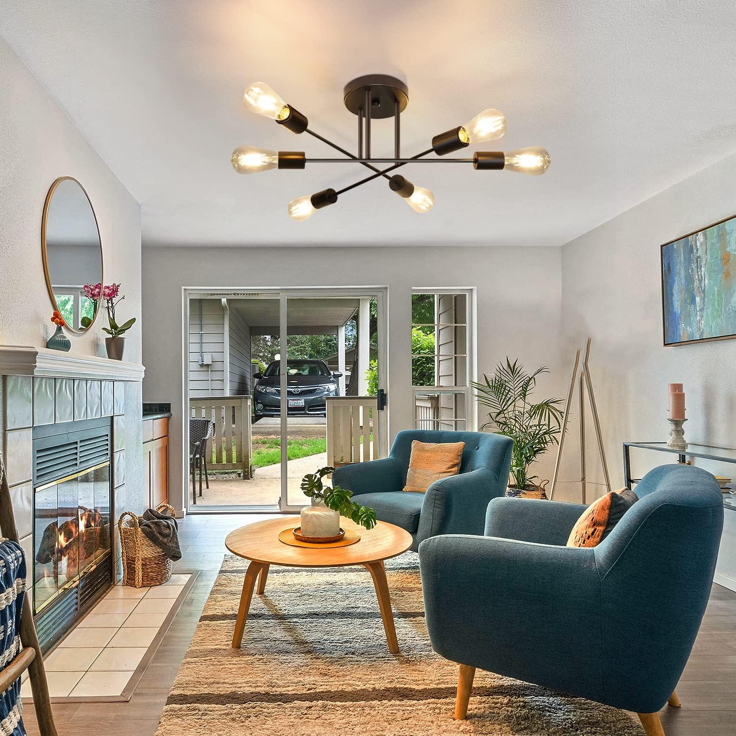Salon z turkusowymi fotelami, dywanem, stolikiem kawowym, kominkiem i lampą sufitową. Na zewnątrz widoczny jest samochód.