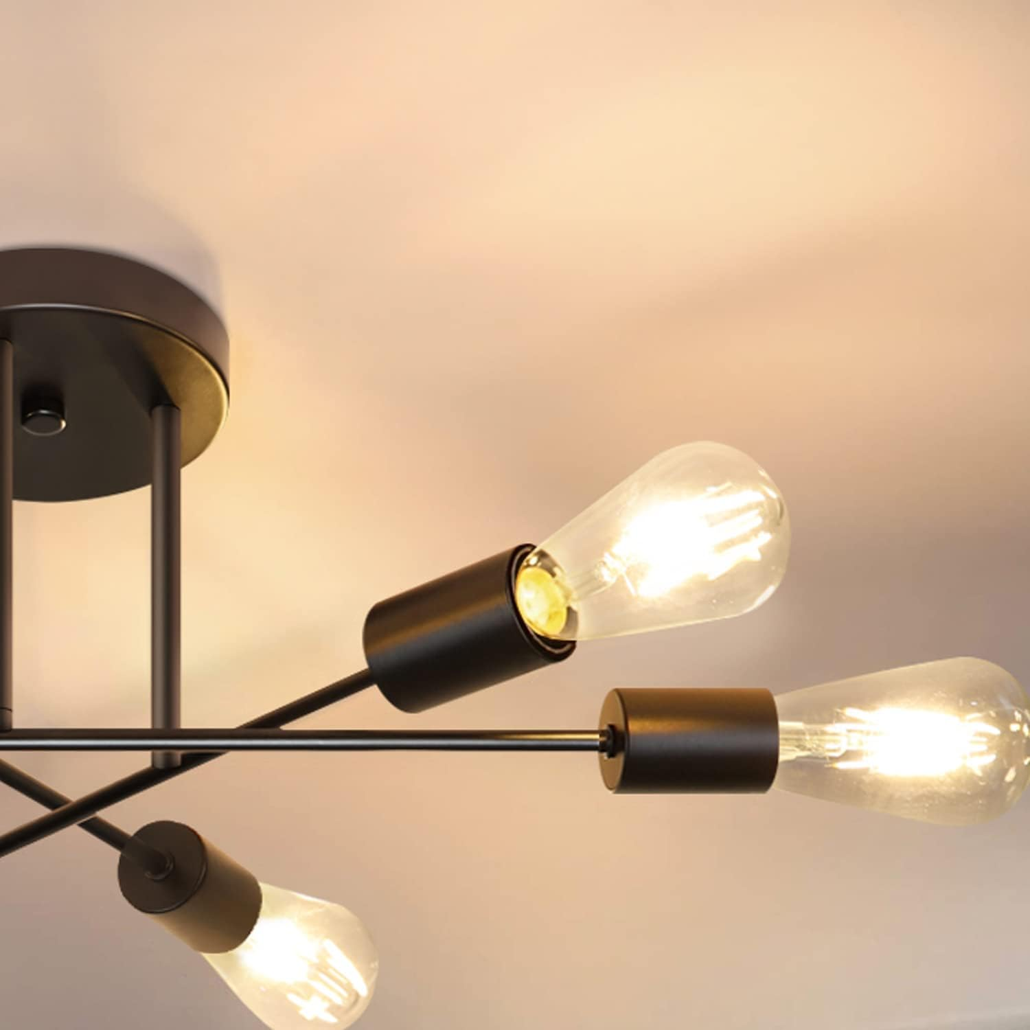 Zbliżenie lampy sufitowej z trzema odsłoniętymi żarówkami. Oprawa jest czarna, z białym sufitem w tle.