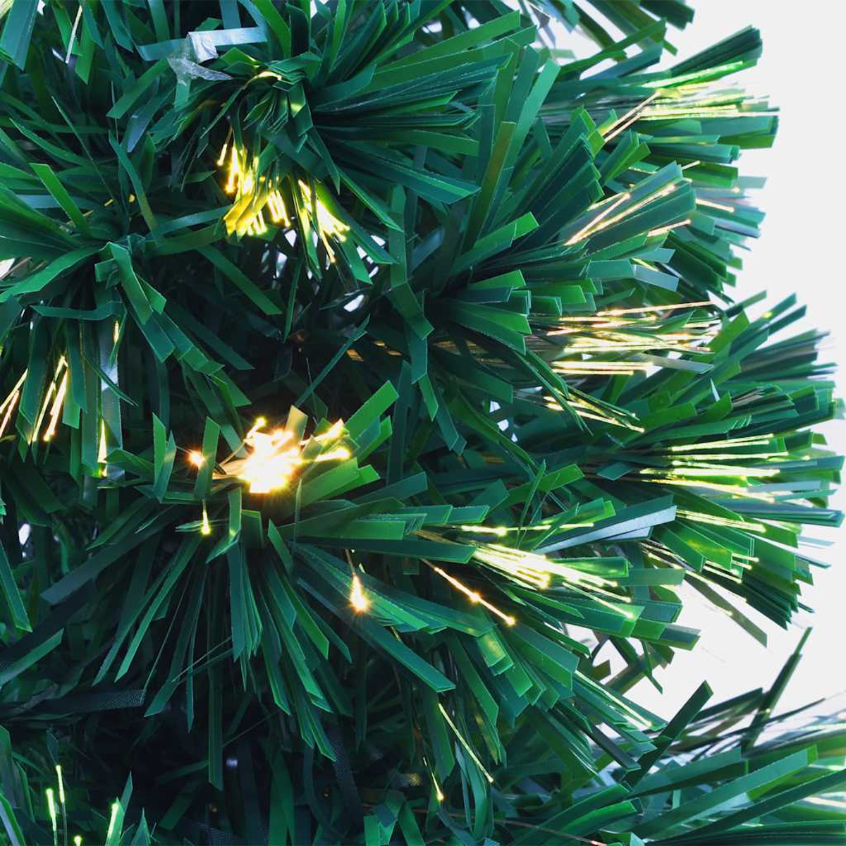 Nahaufnahme eines grünen künstlichen Weihnachtsbaums mit hellen, goldenen Lichtern. Der Hintergrund ist weiß.