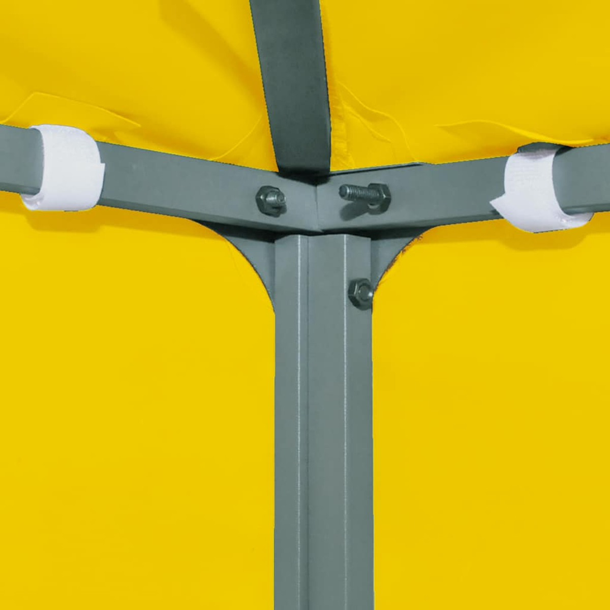 Primo piano della struttura di una tenda. Travi metalliche grigie collegate con bulloni e cinghie di tessuto bianco. Tessuto giallo della tenda sullo sfondo.