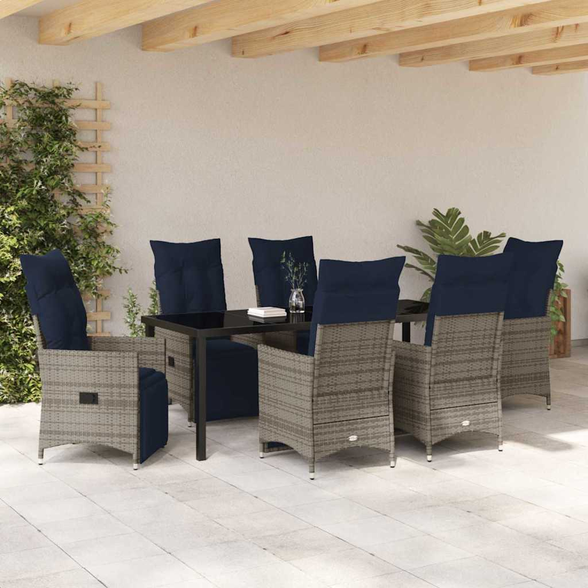Essgruppe im Freien. Sechs graue Korbstühle mit marineblauen Kissen umrunden einen schwarzen Tisch. Die Szene spielt auf einer Terrasse.