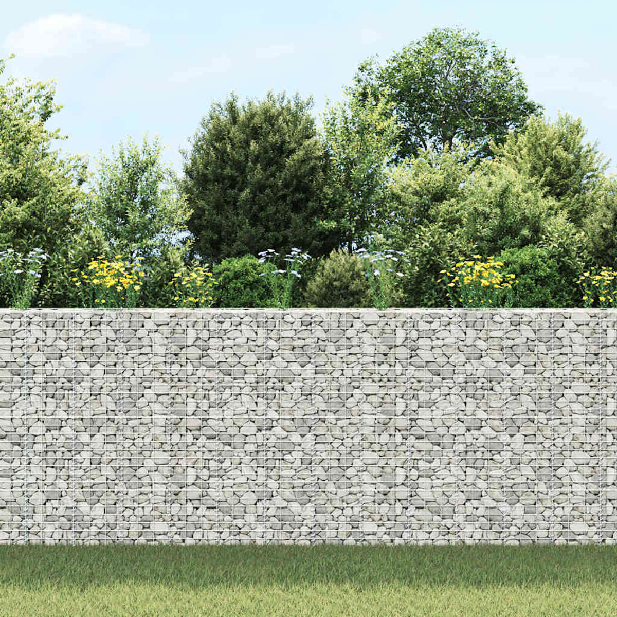 Eine Steinmauer mit Grünzeug oben. Bäume und Büsche befinden sich hinter der Mauer. Im Vordergrund befindet sich Gras, darüber ein blauer Himmel.