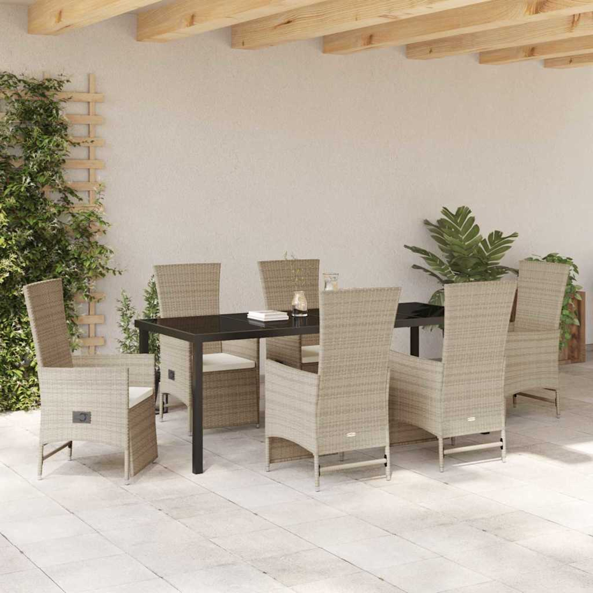 Essgruppe im Freien mit einem schwarzen Tisch und beigefarbenen Korbstühlen. Grüne Pflanzen und ein Holzgitter sind zu sehen.