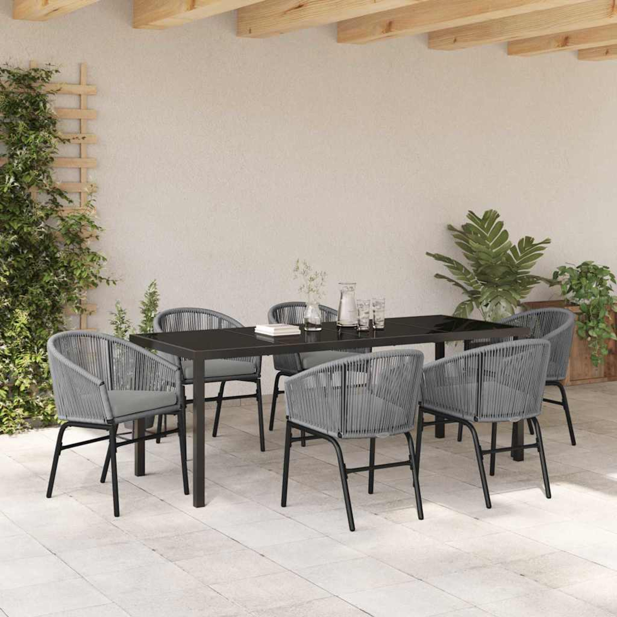Essgruppe im Freien mit schwarzem Tisch und grauen Stühlen. Links sind Pflanzen und ein Gitter zu sehen.